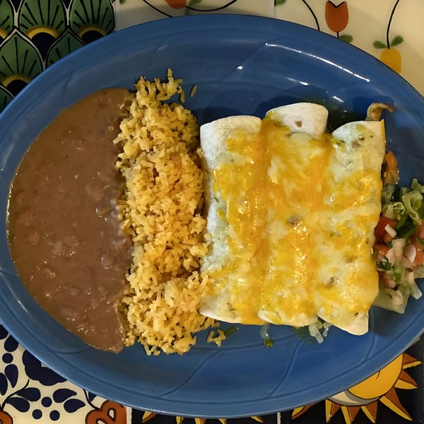 Cafe Bueno's enchiladas with melted cheese, rice, refried beans, and a side salad on a blue plate.