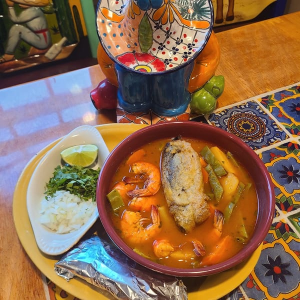 Cafe Bueno's seafood soup with shrimp, fish, and vegetables, served with lime, cilantro, and onions.
